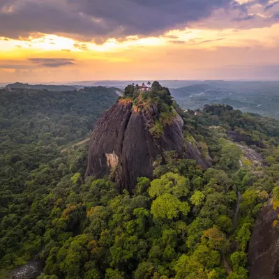 A wider view of the ancient Shiva temple mentioned in the Ramayana. This aerial shot captures the temple and the monolithic rock it sits on against the backdrop of a beautiful sunset.