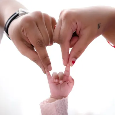 The beginning of everything. The hands of a mother and father join with their newborn's tiny fingers to form a heart, a simple yet powerful symbol of their new family.