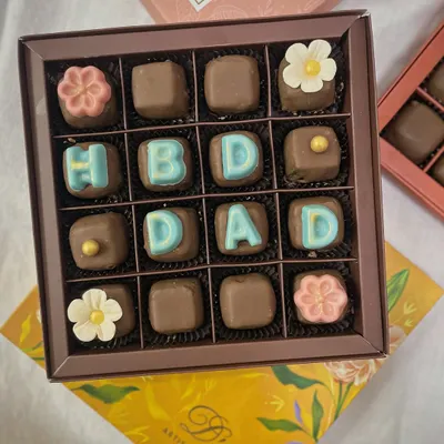 Surprise your loved ones with a box of customized chocolates. This set wishes "HBD DAD" and is adorned with delicate sugar flowers, making it a sweet and personal gift.