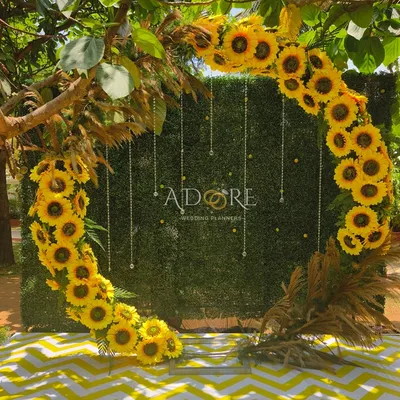A 'Sunflower Aura' selfie booth. This circular arch made of bright sunflowers against a green hedge wall provides a cheerful and vibrant spot for guests to take photos.