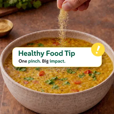 One pinch can make a big impact. Here, we're sprinkling a bit of spice over a bowl of freshly cooked dal. This image highlights our healthy food tip about using simple, traditional ingredients to enhance both flavour and nutrition in everyday cooking.