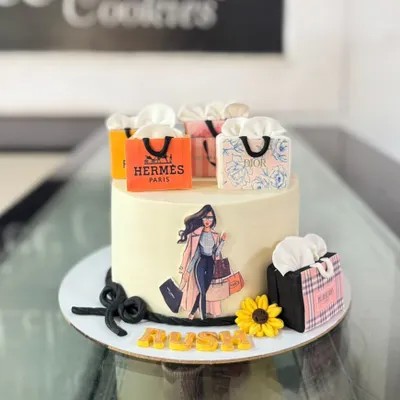 A fashion lover's dream cake, decorated with edible shopping bags from luxury brands like Hermes and Dior. It's a chic and stylish centerpiece for a birthday.
