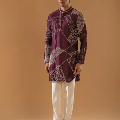 A deep plum kurta featuring modern, geometric threadwork. This piece reflects the finesse of artisanal craftsmanship and the quiet confidence of the modern gentleman, tailored to perfection.