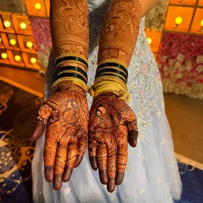 A stunning example of full bridal mehendi, with matching intricate designs on both hands and arms, featuring peacocks and elephants.