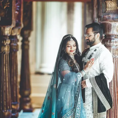 A quiet, intimate moment between a couple in beautiful traditional attire. The soft lighting and the historic-looking corridor create a timeless, romantic feel.