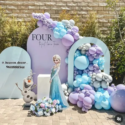 An elegant outdoor Frozen-themed party setup for a fourth birthday. The design features Queen Elsa and Olaf cutouts, a beautiful balloon cascade in pastel purple and blue, and custom arched backdrops for a sophisticated look.