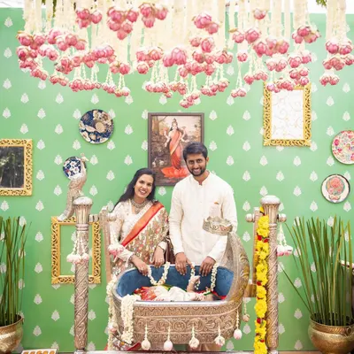 The happy family at their daughter Tridha's naming ceremony. The decor features a beautiful silver cradle and a backdrop inspired by Ravi Varma paintings.