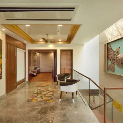This third-floor lobby in Kavyam Residence combines elegance with functionality. It features marble flooring, a wooden-accented ceiling, and eye-catching artwork, including a laser-cut bird mural.