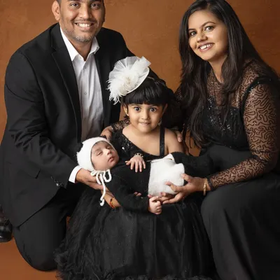 A beautiful family portrait celebrating their newest member. The coordinated black attire adds a touch of formal elegance, making this a classic keepsake for generations to come.