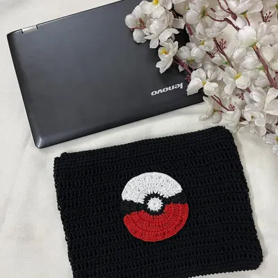 A handmade crochet laptop sleeve with a Pokémon theme, shown here next to a laptop for scale. It's a fun and protective way to carry your tech.