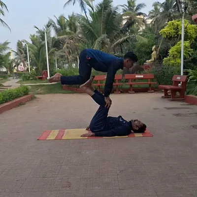 This is the level of strength, balance, and trust we build in our partner yoga sessions. Here, one of my students acts as a stable base while the other performs an advanced balancing posture, demonstrating incredible core control and coordination in an outdoor park setting.