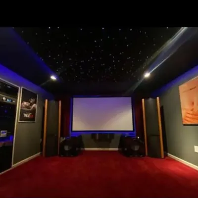 A classic home cinema design featuring a starlight ceiling, rich red carpeting, and strategically placed tower speakers for an authentic and powerful audio-visual experience.
