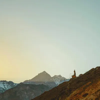 A solitary Buddha statue overlooking the mountains of Spiti Valley at dawn. This image captures the peaceful, spiritual feeling of the Himalayas, with the first light hitting the distant peaks.