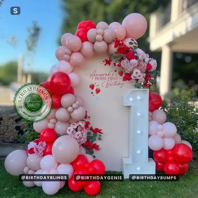 A "Berry First Birthday" theme is a sweet way to celebrate turning one. This outdoor setup features a beautiful balloon arch in shades of red and pink, with a large light-up number '1'.
