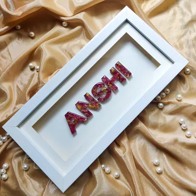 This is a wide view of the custom "Anshi" name frame, showcasing how it looks as a complete decor piece. The name is crafted from resin filled with real flower petals and mounted in a clean, white shadow box.