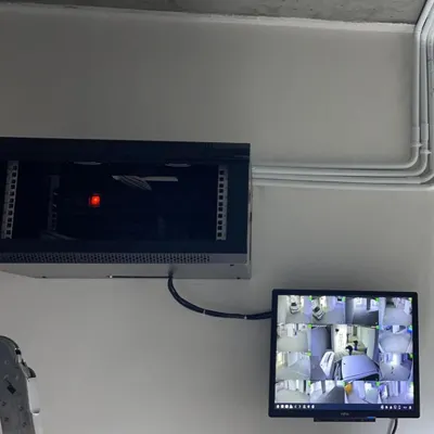 A finished installation showing the wall-mounted server rack and a dedicated monitoring screen. All wiring is neatly channeled through conduits for a clean look.