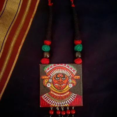 This hand-painted pendant is my tribute to Theyyam, an ancient ritual dance form from Kerala. I've used a rich palette of reds and intricate details to capture the divine energy of the performance on a small canvas.
