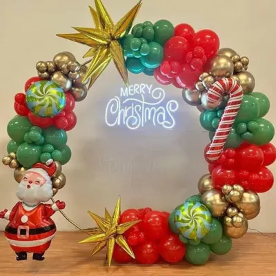 This Christmas-themed balloon wreath is a popular choice for both home and office parties. It combines traditional red and green with metallic gold balloons, a neon sign, and fun accents like a Santa figure and candy cane balloons.