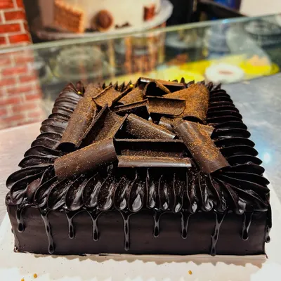 A classic Death by Chocolate cake, featuring rich chocolate ganache, chocolate drip, and delicate chocolate curls.