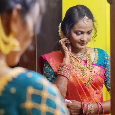 A beautiful "getting ready" shot of the bride. Capturing her reflection as she puts on her earrings, this photo highlights her anticipation and the stunning details of her bridal look.