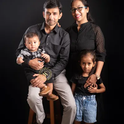 A beautiful portrait of a family of four. We arranged this shot to feel connected and warm, with the parents and children close together against a classic dark studio background.