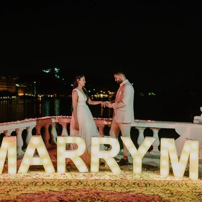 The perfect setup for the most important question. I designed this romantic lakeside proposal with large 'MARRY ME' marquee letters, creating a magical and unforgettable moment against the glittering city lights.