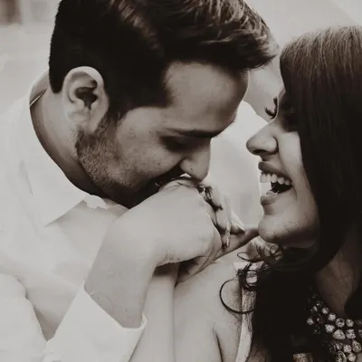 A sweet, candid moment captured during a pre-wedding shoot. The sepia tone gives this photo a warm, nostalgic feel, perfectly capturing the couple's natural chemistry and affection.
