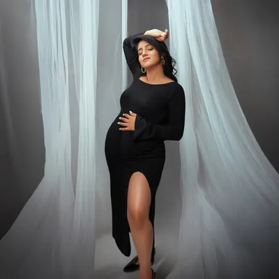 A chic and modern maternity portrait. The flowing white fabric and the elegant black dress create a high fashion look, celebrating the beauty and strength of the female form.