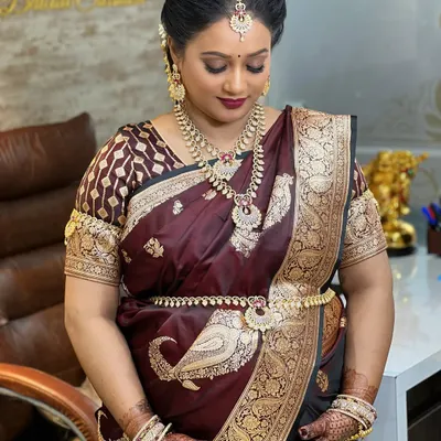 A beautiful mom-to-be at her baby shower, glowing in a traditional silk saree. She is wearing a stunning temple jewellery set, including layered necklaces and a waist belt (kamarbandh).