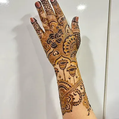 This elegant back-hand design extends up the arm, featuring beautiful jhumka (earring) motifs. The combination of floral patterns and delicate chains creates a jewelry-like effect.
