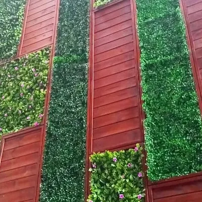 This is a close-up of a large-scale artificial green wall I designed with integrated red-brown wood paneling. The vertical and horizontal lines create a dynamic, modern pattern that completely redefines the building's exterior.