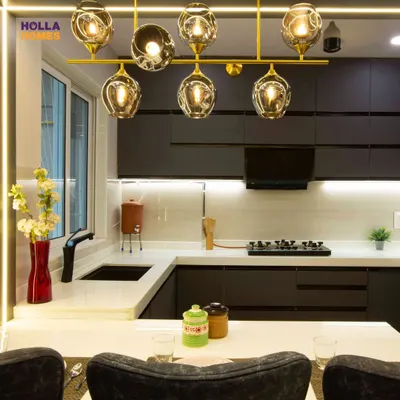This stunning open kitchen features dark, sleek cabinets, a white countertop, and a beautiful gold chandelier that doubles as a dining light. It's a perfect example of modern luxury.