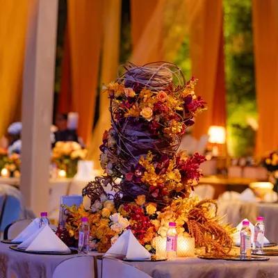 This sculptural centerpiece was inspired by the work of international designer Hitomi Gilliam. It utilizes midollino extenders to create a woven, nest-like structure from which autumn-toned flowers appear to grow organically.
