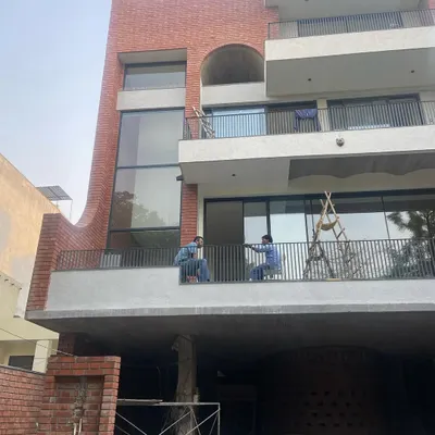 The facade of 'The Waterfall' house in Noida taking shape. This view shows the multi-level balconies and large glass openings that will define the building's exterior, with the sculptural brick element visible at the base.