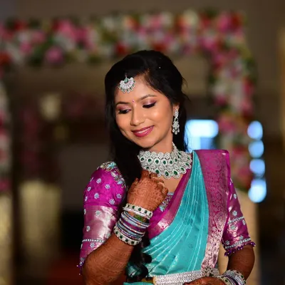 A picture-perfect reception look for Apoorva. The makeup features soft, shimmery eyes and a gentle pink lip, paired with diamond jewellery and a beautiful turquoise and pink saree.