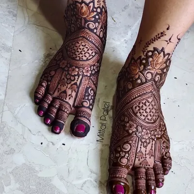 A stunning example of full-coverage bridal foot mehndi. The design is intricate and dense, featuring beautiful floral and paisley patterns that extend from the toes to the ankles.