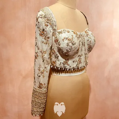 A modern heirloom for Shahin Begum. This corset-style blouse in soft beige raw silk with flowing georgette sleeves is a blend of contemporary charm and traditional finesse.