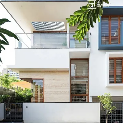 The front elevation of the Cube House. The design uses clean white planes, travertine cladding, and carefully placed windows to create a modern and inviting facade on a compact city plot.