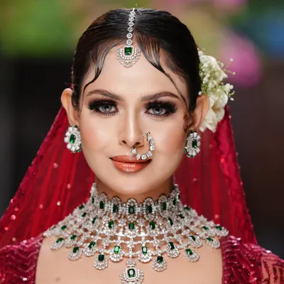 A picture of bridal perfection. This student's work showcases a classic look with emerald jewelry, featuring sharp winged liner, soft contouring, and a glossy nude lip, ideal for the modern bride.