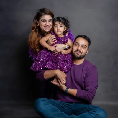 A family that glows together, grows together. The coordinated purple outfits look wonderful against our simple studio backdrop, making their smiles shine.