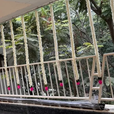 Simple and elegant balcony decor for a housewarming. We used strings of white flowers with bright pink tassels, adding a touch of tradition and color to the outdoor space during the daytime.