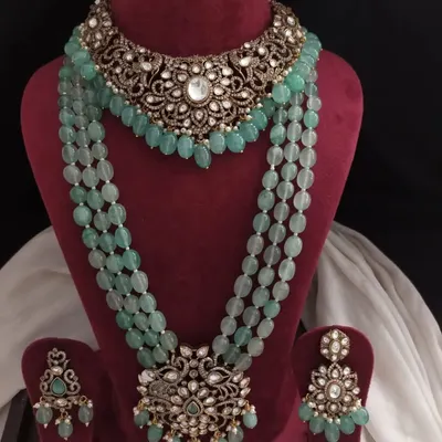 This stunning Victorian-inspired jewelry set features a choker and a matching long beaded necklace in a beautiful pastel green. The intricate metalwork is studded with stones for a grand, royal look.