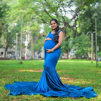 Embrace your bump with this elegant royal blue mermaid gown. The fitted design beautifully accentuates your curves, while the small train at the bottom adds a touch of classic glamour to your outdoor maternity shoot.
