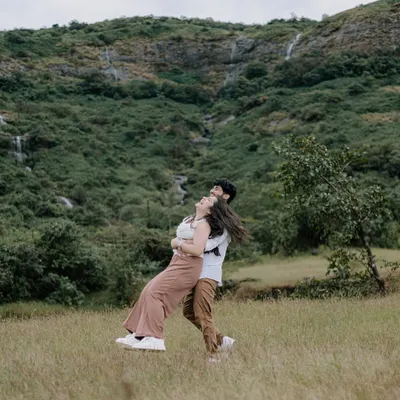 A joyful, carefree twirl in the middle of a lush green meadow, with mountains in the background. This photo is full of movement and happiness, perfectly capturing a spontaneous moment of love.
