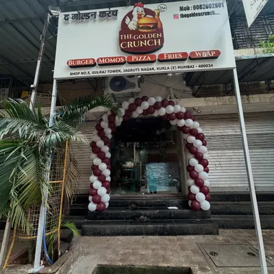 A classic spiral balloon arch in maroon and white perfectly frames the entrance for the grand opening of 'The Golden Crunch' restaurant, creating an inviting and festive look.