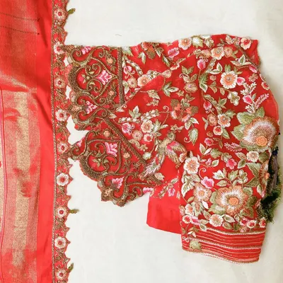 This is a detailed view of a sleeve I crafted for a bridal blouse. The vibrant red net is densely covered in floral and bird motifs, created with fine threadwork. The scalloped cut-work border adds a soft, romantic finish, highlighting the precision of the hand embroidery.