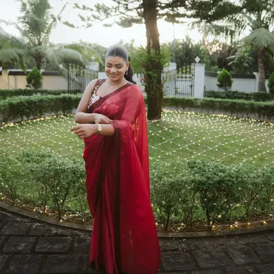 Samerah, radiant in a beautiful red saree, during her engagement ceremony. This portrait captures her happy anticipation in a lovely garden setting adorned with fairy lights.
