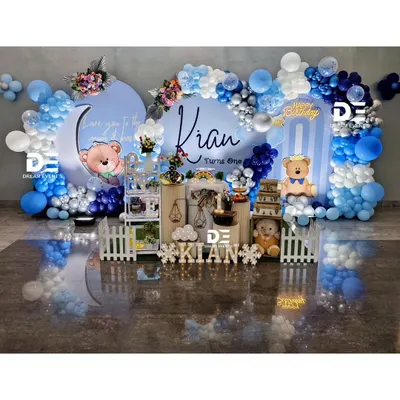 A dreamy 'Love you to the moon and back' teddy bear theme for Kian's first birthday. This elaborate setup features two circular backdrops, a beautiful blue and silver balloon garland, and adorable teddy bear cutouts.
