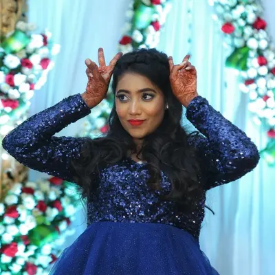 A fun and playful shot of the bride-to-be at her reception. The makeup features a classic red lip and defined eyes, a perfect match for her sparkling blue gown.