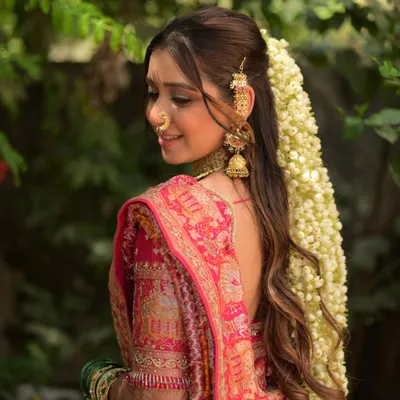 A close-up of this stunning bridal hairstyle. The cascade of fresh jasmine flowers, known as gajra, paired with a traditional hair accessory, creates a look that is both romantic and timeless.